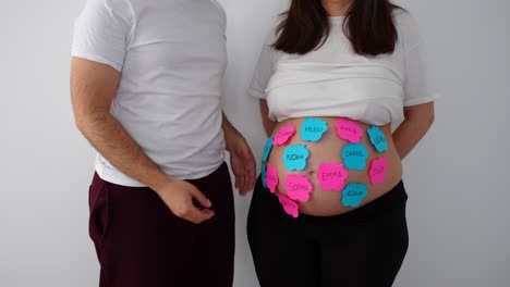 expecting parents can't decide baby name, pregnant belly with sticky notes showing names
