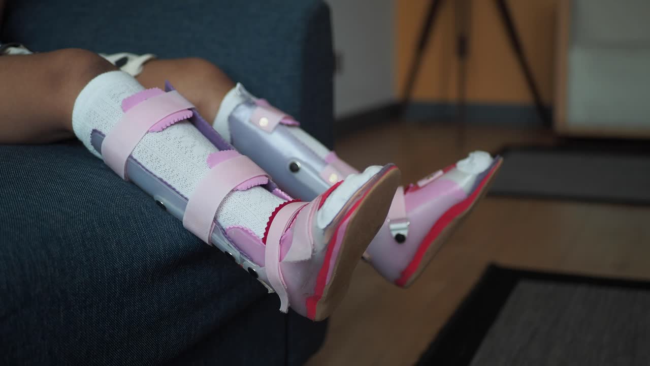 niño con soporte para la pierna sentado en un sofá