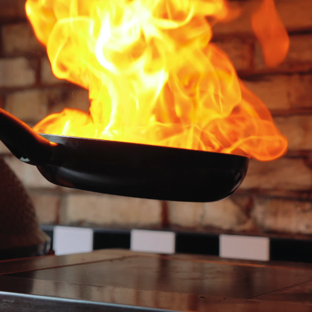 Chef sautes mushrooms with flames in restaurant while flipping around food. Professional cooking. Sqare video