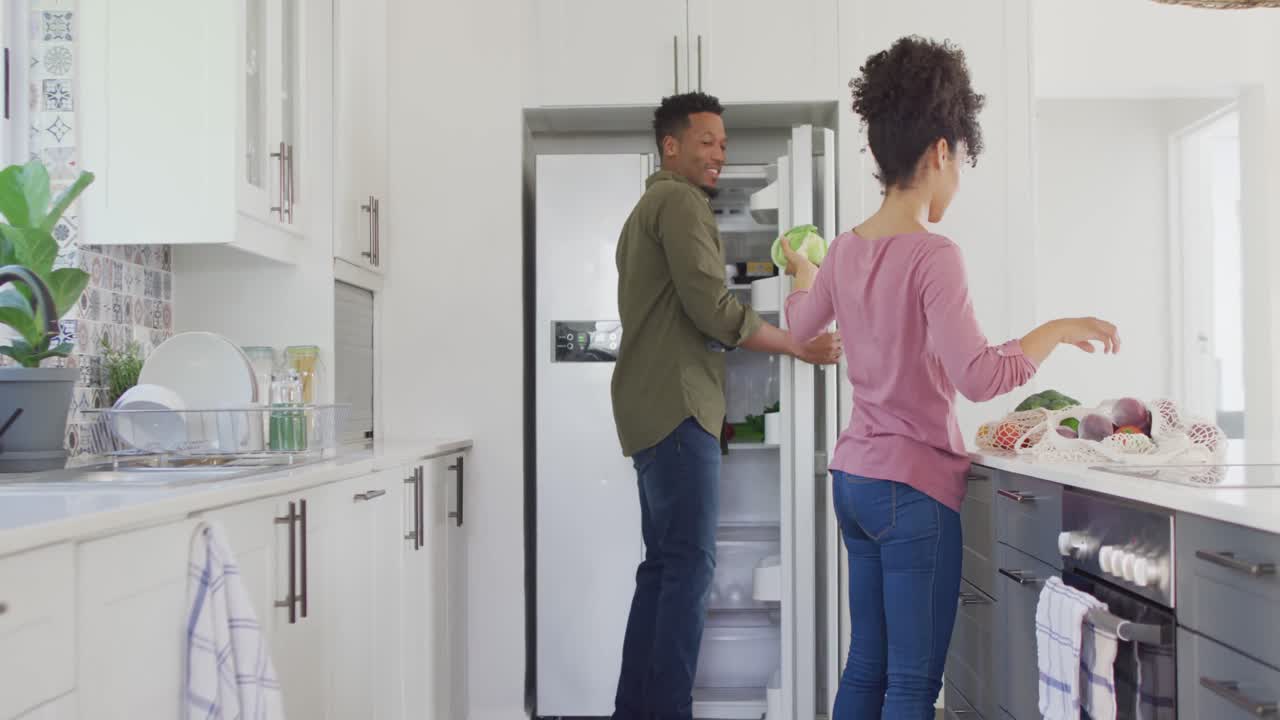 feliz pareja afroamericana con verduras en la cocina