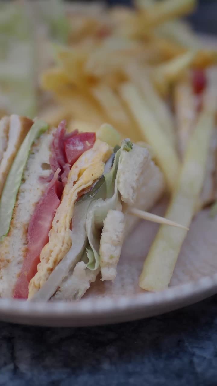 Delizioso Club Sandwich con patatine fritte servito su un piatto.