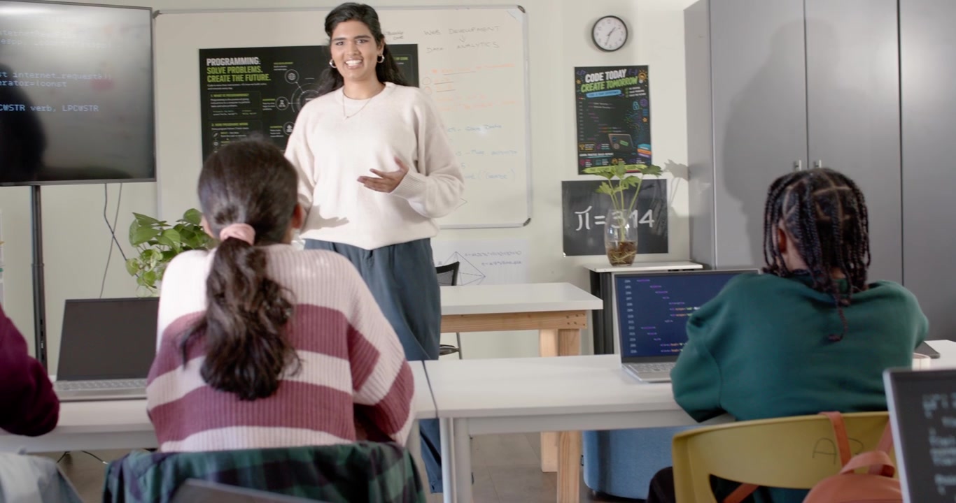 Cámara alejándose revelando a un profesor indio presentando código y enseñando programación a adolescentes en clase