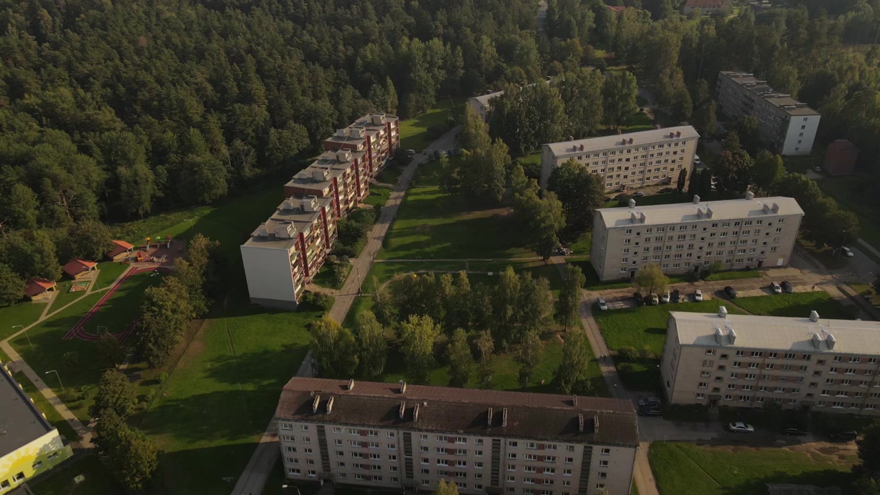 Вид с дрона на небольшой городок Лиепа, залитый прекрасным дневным светом. Сцена запечатлевает здания, улицы и окружающую зелень в безмятежном сельском пейзаже.