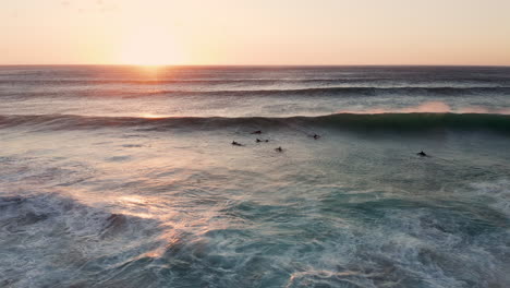 Aerial-View-Of-Surfers-On-The-Wave-In-Llandudno,-Cape-Town-At-Sunset---drone-shot