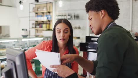 Video-of-happy-diverse-female-and-male-waiters-in-aprons-working-at-coffee-shop