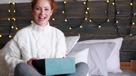 happy girl opening christmas gifts in bed