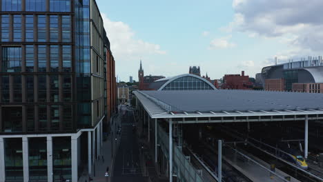 Ascending-view-of-modern-buildings-in-town.-Flat-roof-above-platforms-at-train-station.-Clock-tower-of-St-Pancras-in-distance.-London,-UK