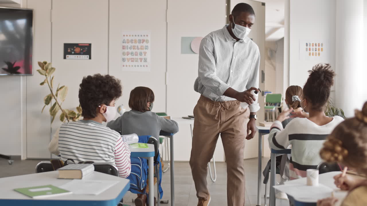Schoolchildren Disinfecting Hands with Sanitizer during Lesson