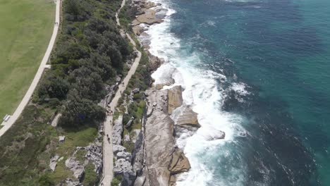 Turistas-Paseando-Por-La-Costa-Con-Olas-Blancas-Espumosas---Playa-Bondi-En-Verano-En-Sydney,-Nsw,-Australia