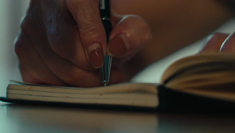 close up of senior woman right hands writing a book notebook journal