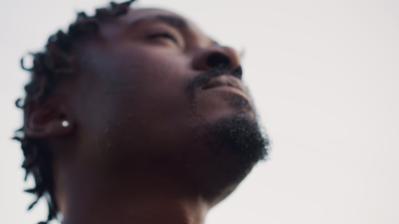 Upward Angle Scout Drinking Ruby Drink Against Bright Sky, Relaxed Neck Tilt, Swallowing Motion, Beard And Earring Visible, Silhouette Effect From Backlight, Calm Resilient Mood, Outdoor Expedition
