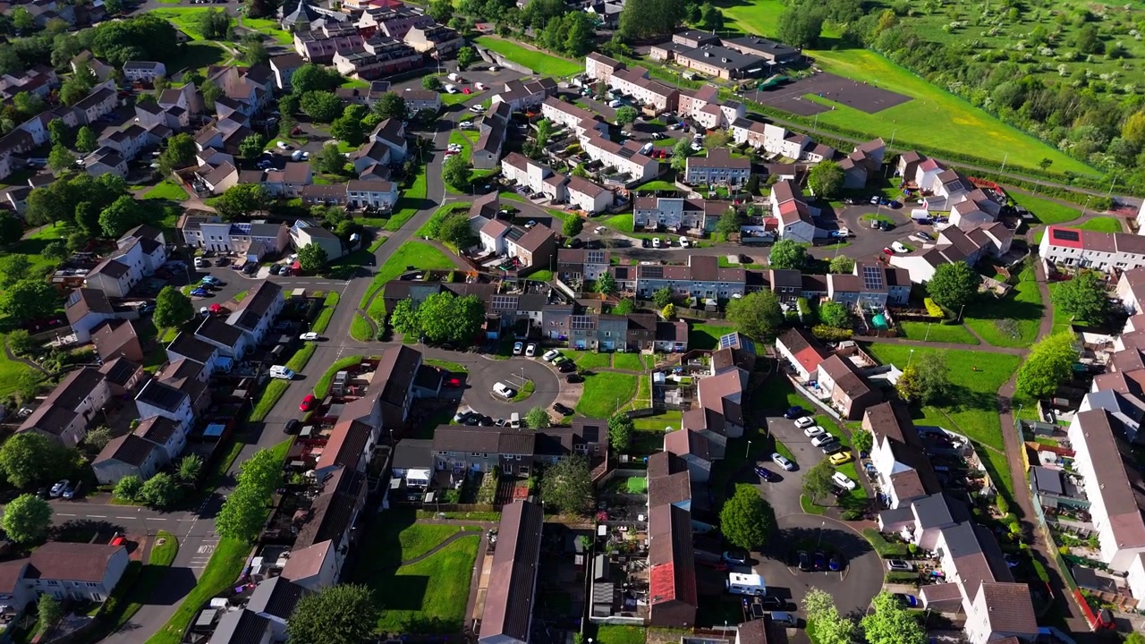 Bourtreehill Village, North Ayrshire, Skotland, viser en typisk beboelseslandsby nær en by, med huse, gader, grønne områder og omkringliggende landskab, luftfoto