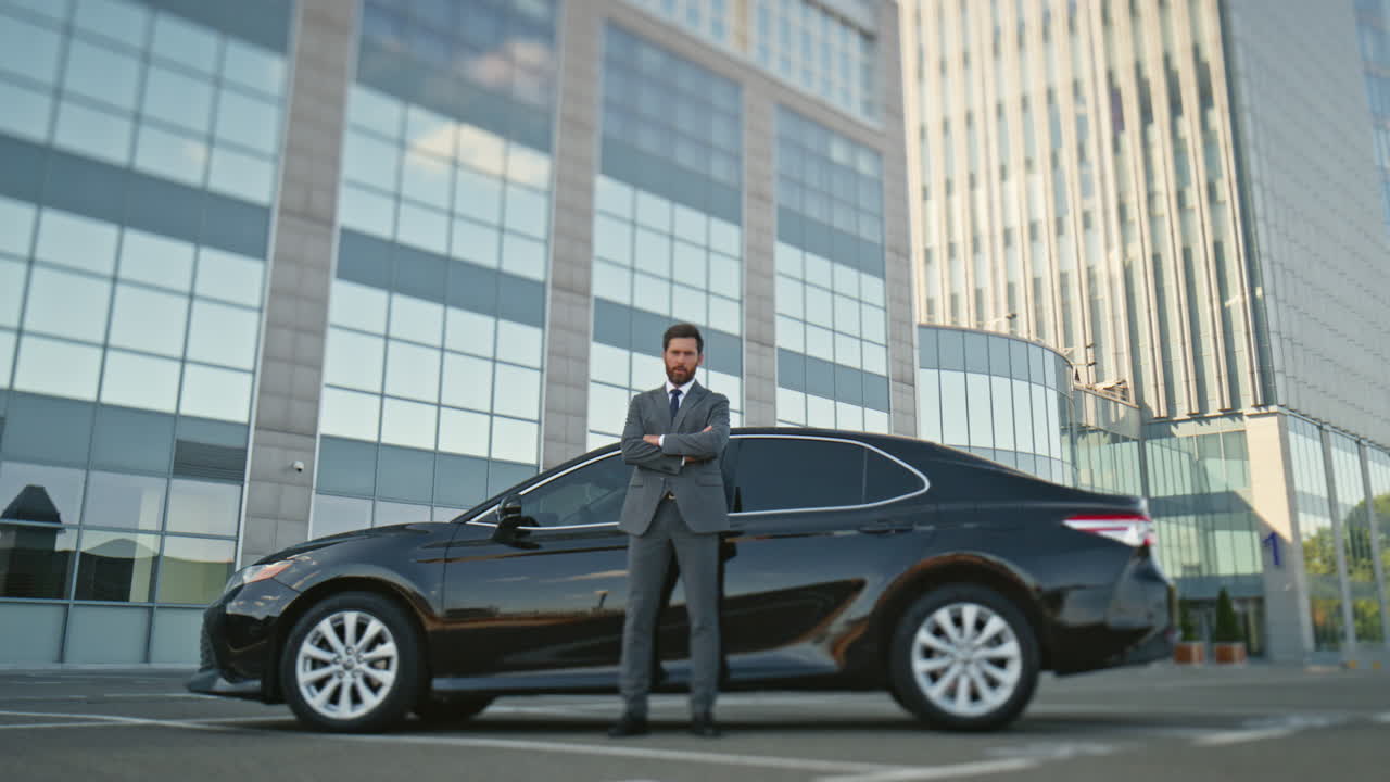 orgulloso dueño de un coche posando en un automóvil negro en la calle.