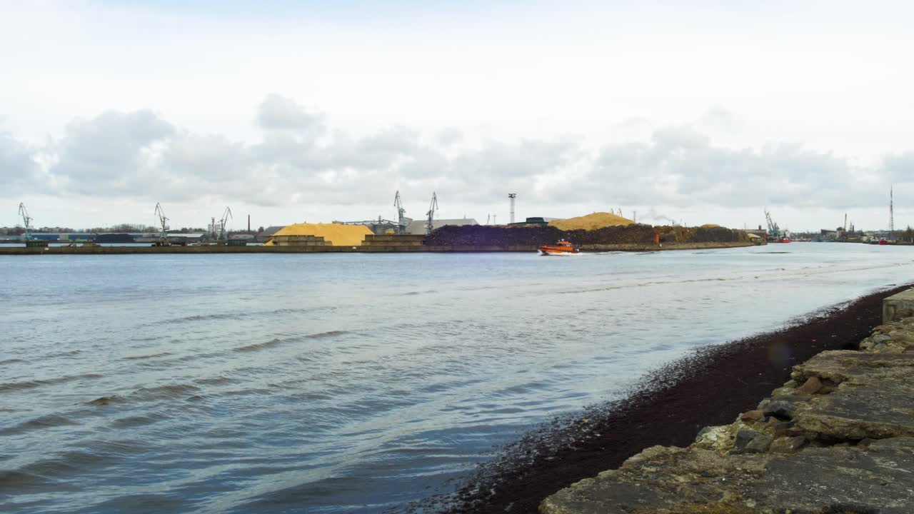 Navio-piloto laranja do porto saindo do Porto de Liepaja, dia nublado de primavera, plano de acompanhamento amplo com câmera na mão