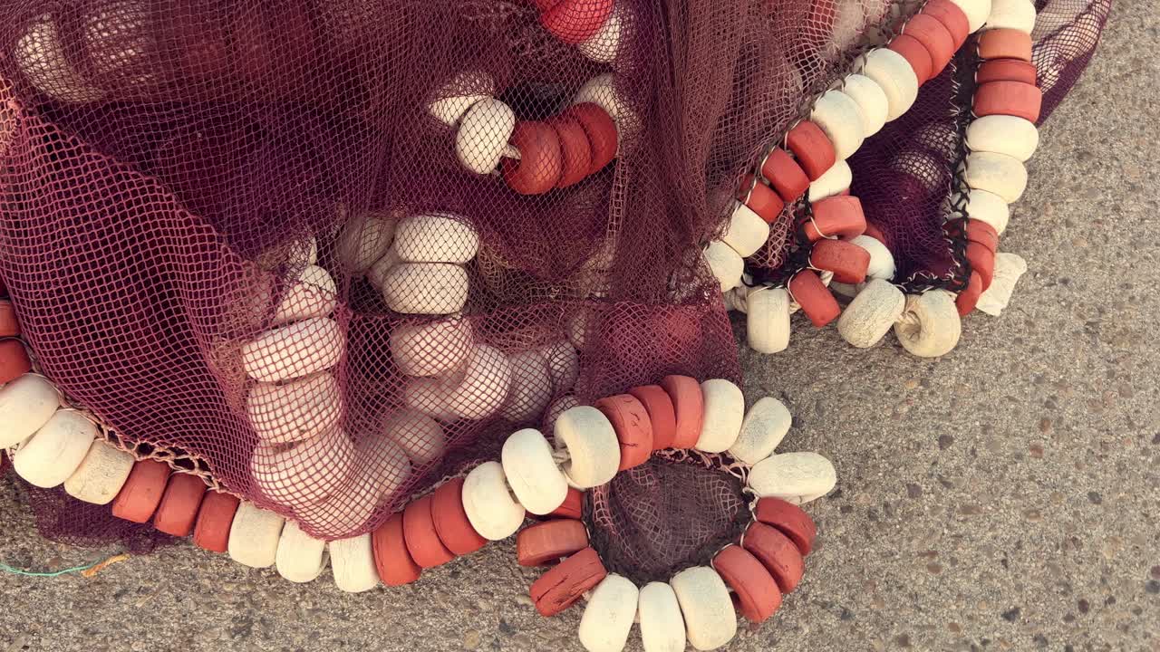 toma de video giratoria de una pila de pilas de redes de pesca y aparejos, una gran pila tendida en la superficie de asfalto al aire libre en el almacén, concepto de la industria pesquera