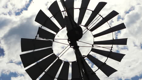 Nahaufnahme-Einer-Windmühle-In-Vollem-Betrieb,-Die-Einen-Kontrast-Zum-Blauen-Himmel-Und-Den-Wolken-Bildet