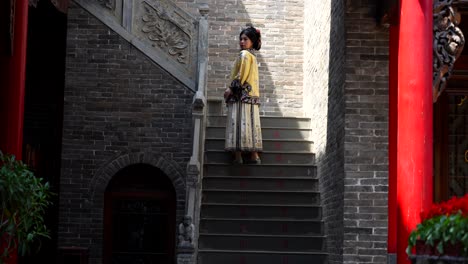 woman dressed in traditional silk qing dynasty clothing climbs stairs and turns to look back