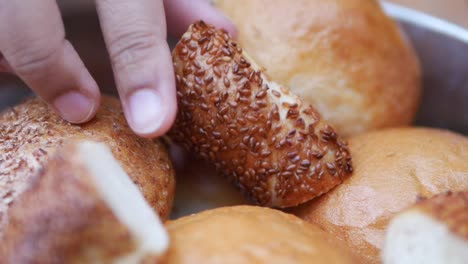 hand picking a sesame bread from a bowl