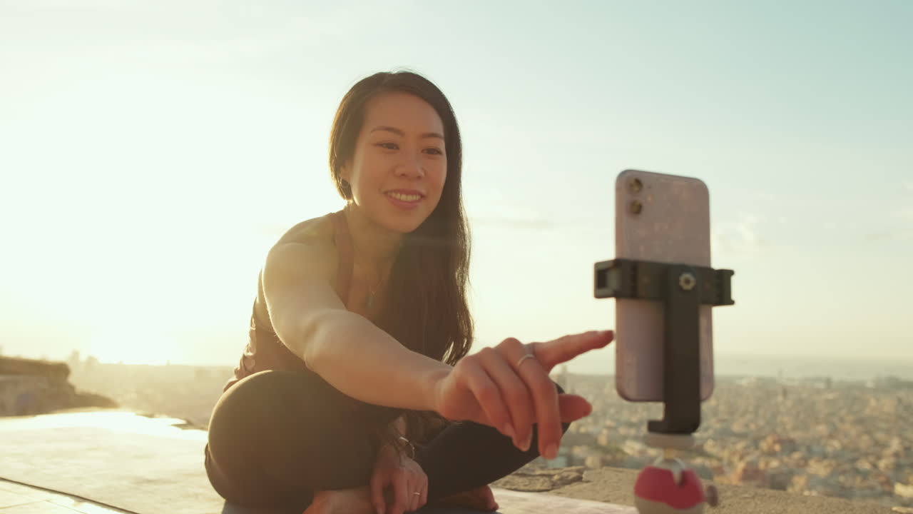 Woman vlogging in front of a cityscape during sunset
