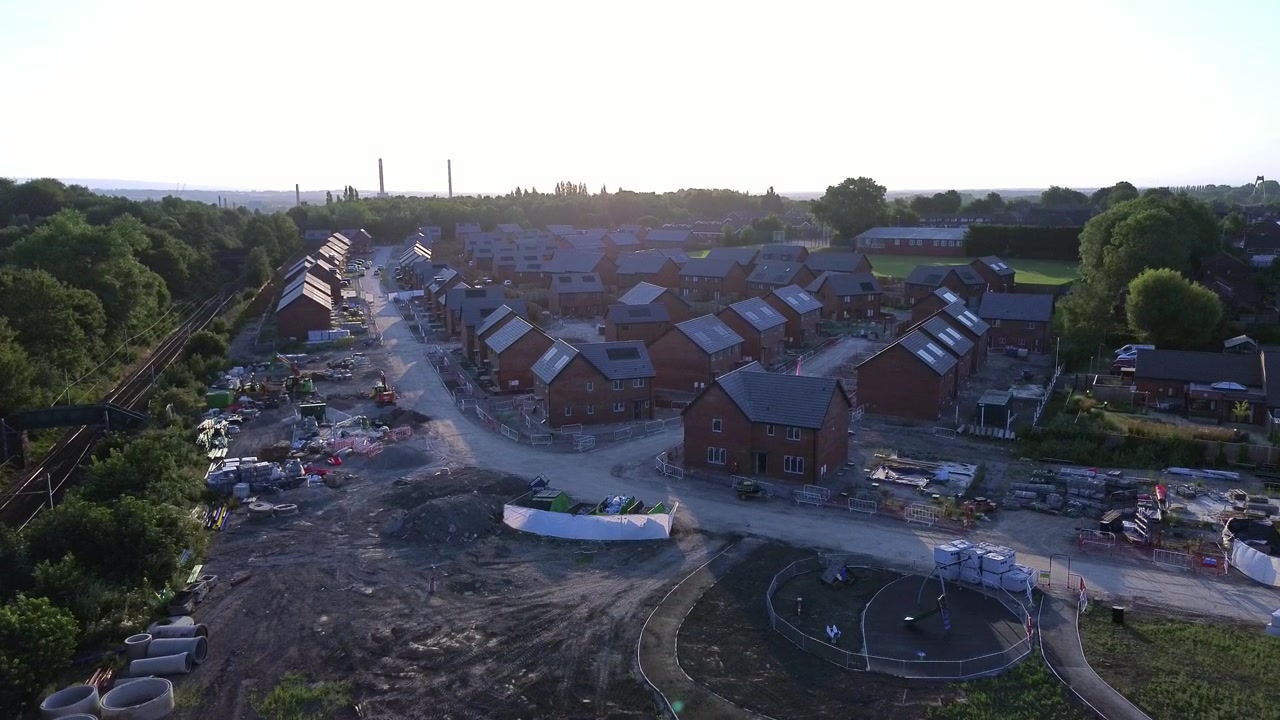 Affordable new home estate construction site aerial rising view over unfinished sunrise development
