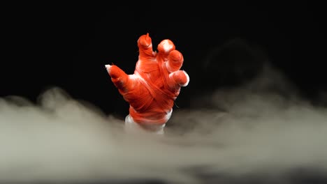 terrible zombie mummy hand in blood rising outfrom the smoke in darks and showing a phone with a
