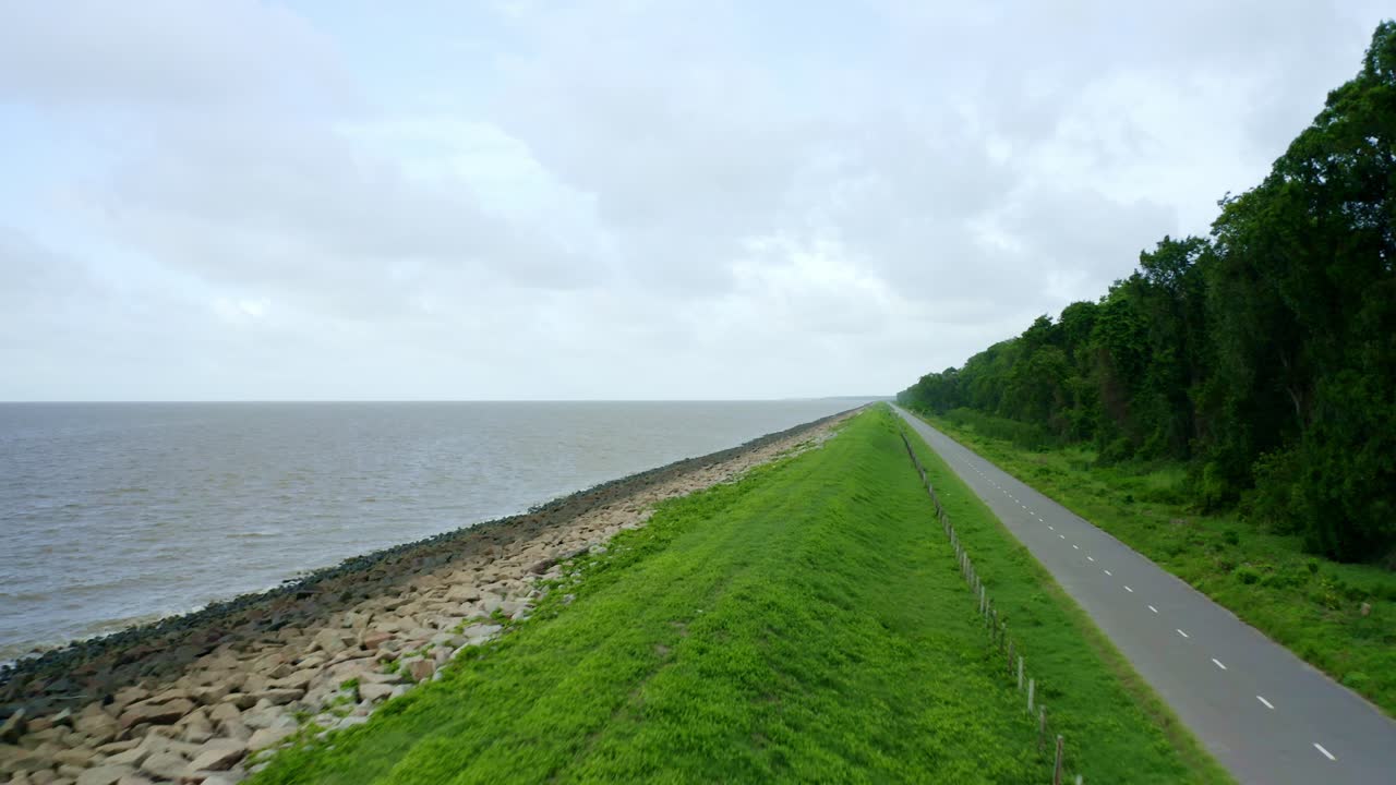Aerial: Sea dyke view along the asphalt road flyover, North Atlantic Ocean and Nickerie Suriname
