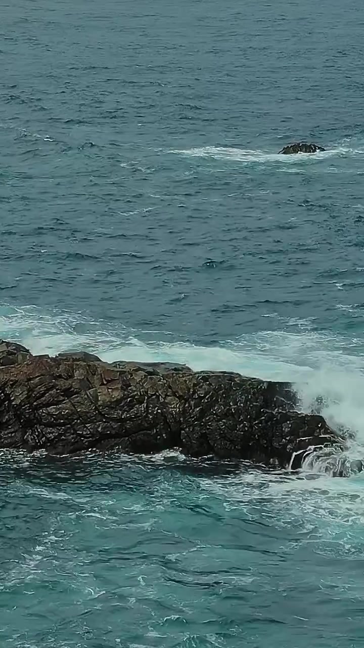 Pemandangan garis pantai berbatu di Tenerife dengan ombak laut dan bebatuan di kejauhan
