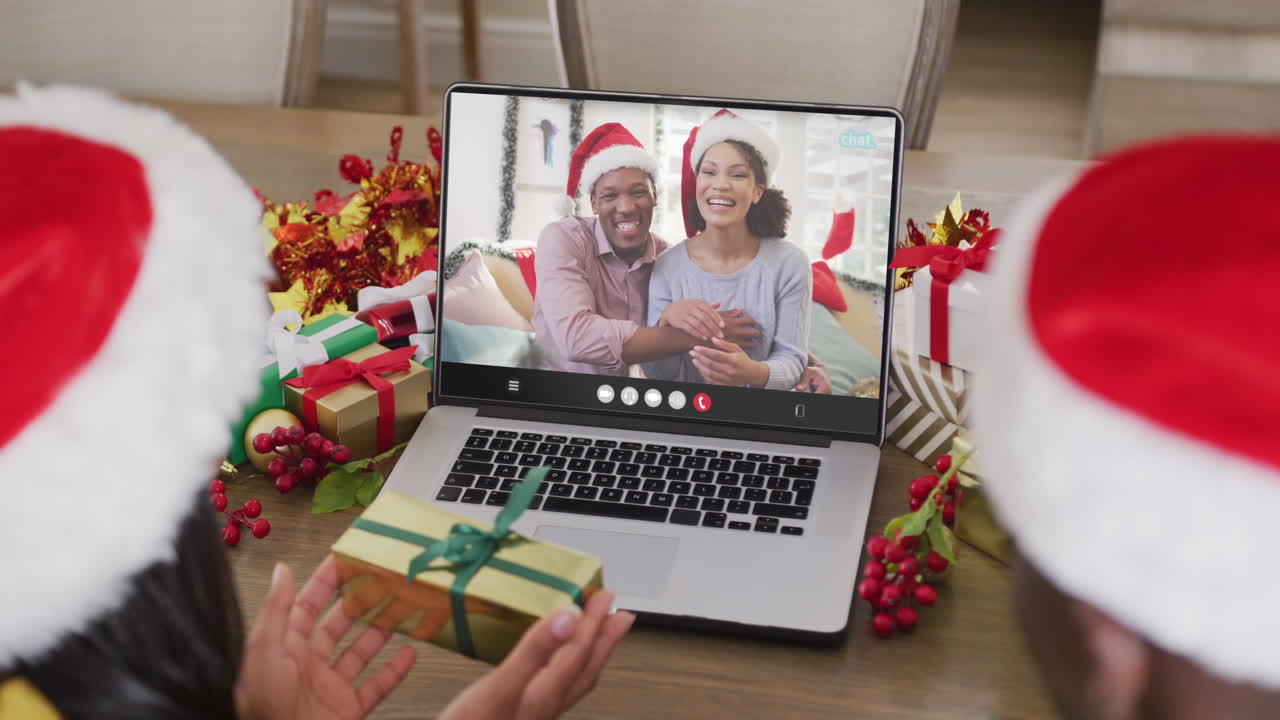 pareja diversa con sombreros de santa teniendo llamada de video portátil con pareja diversa