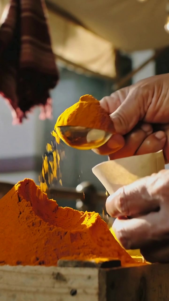 Vertical video: Pinching vendor's bare hands pulling spice scooping spoon into paper cone at market