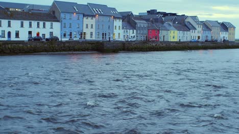 Toma-Inclinada:-Corriente-Del-Río-Corrib-Hasta-Coloridas-Casas-De-Largo-Recorrido,-Galway,-Temprano-En-La-Mañana