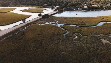 wide shot of inlet at sunset with road to the left over water with canals to the right