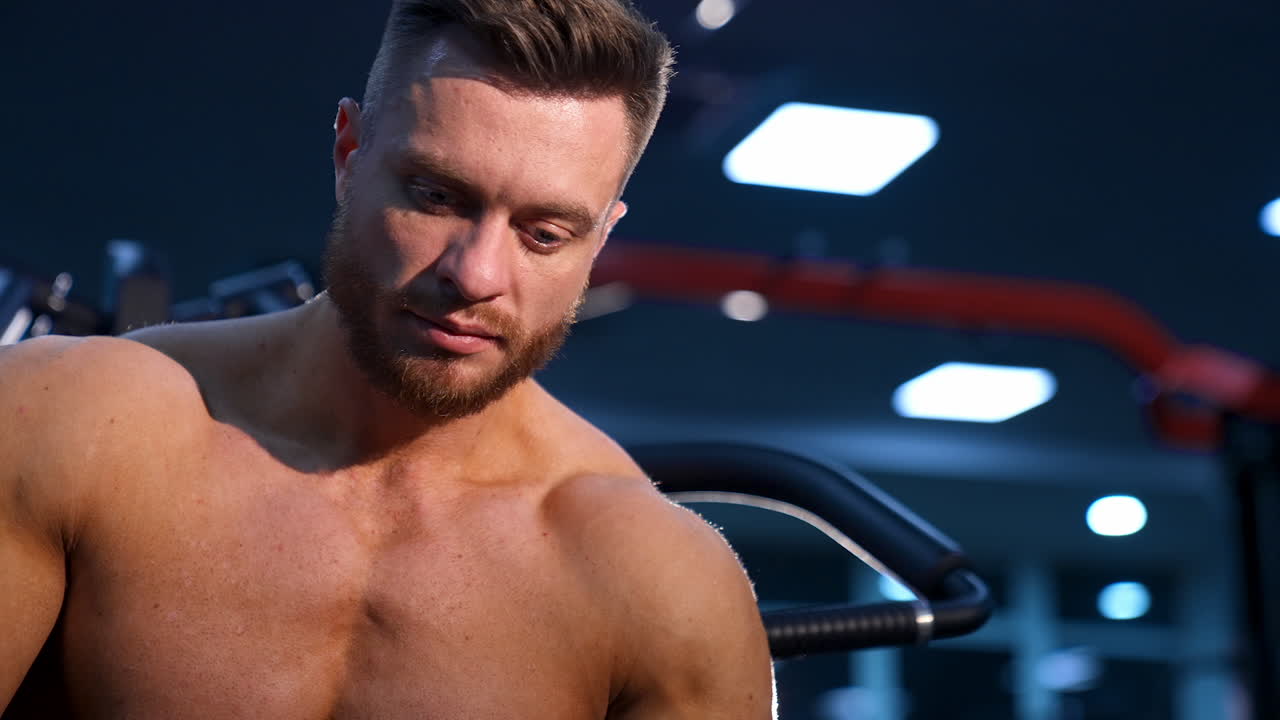 Athlete with strong body poses on modern gym background. View from the bottom.