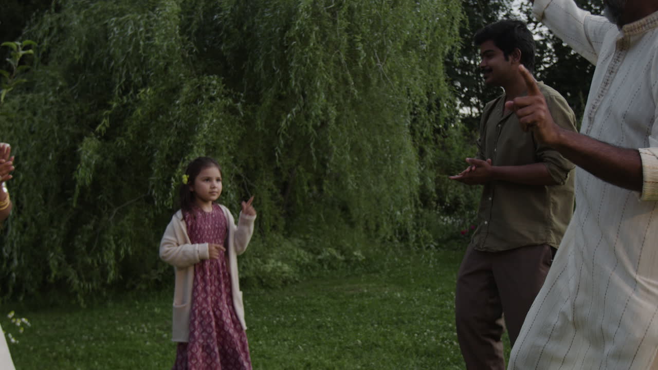 Indian family enjoying outdoor activities with hand gestures in a lush garden
