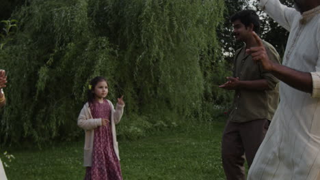 indian family enjoying outdoor activities with hand gestures in a lush garden