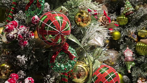 close-up of christmas tree with snow decorated with many colorful balls spins on a turntable - festive winter holidays background