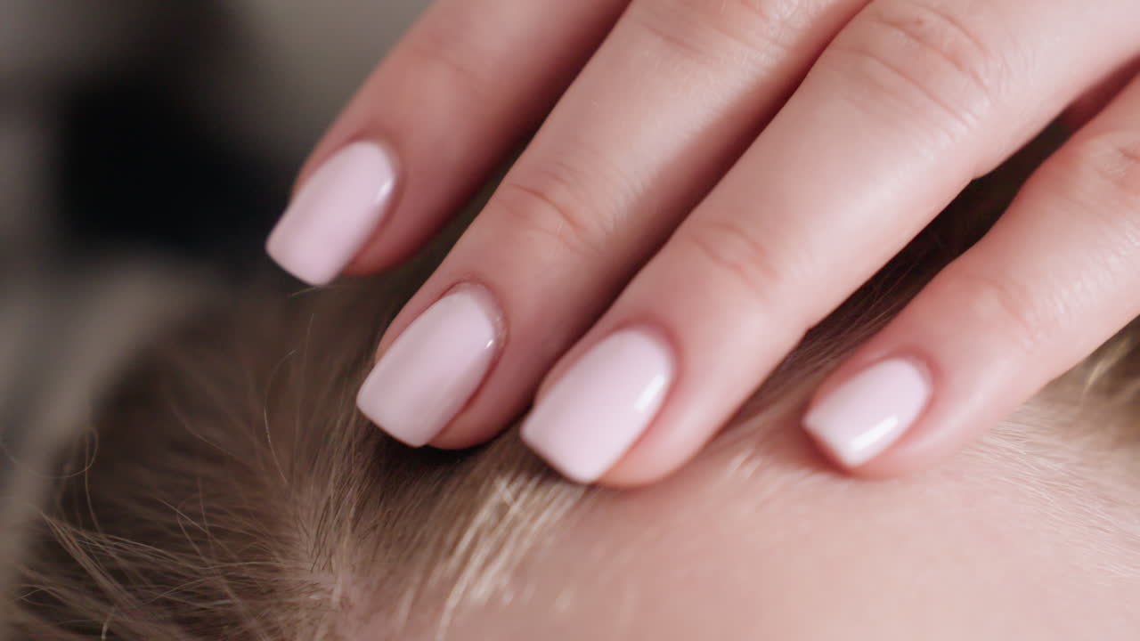 Close up of woman hand with light pink manicure gently touching child hair, capturing tenderness, love, comfort, nurturing bond, maternal care, and emotional warmth in intimate family moment indoors