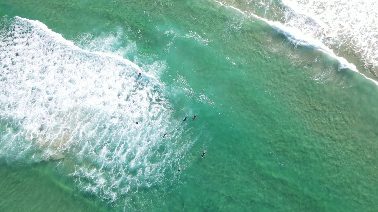 해변에서 굴러다니는 하얀 파도에 떠 있는 서핑보드의 서퍼 - 호주 뉴사우스웨일즈의 본다이 해변에서의 레저 여행