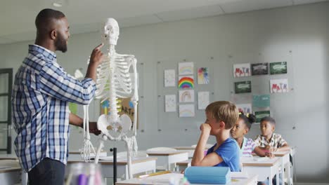 video de un feliz maestro afroamericano con una clase de alumnos diversos durante la lección de anatomía