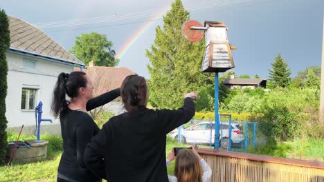 two women and a young girl admire the vibrant rainbow stretching across the clear blue sky in ostrava, czech republic - slow motion