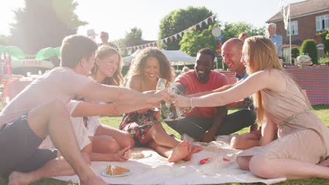 Slow-Motion-Shot-Of-Friends-Sitting-On-Rug-At-Summer-Garden-Fete-And-Making-Toast