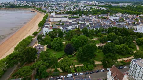 forward drone shot over jardin des plantes in saint-nazaire, showing gardens, beach, sea, and surrounding houses - france