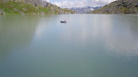 Toma-Aérea-Volando-Sobre-Un-Lago-Aislado-En-Alaska-Con-Un-Hombre-Solitario-En-El-Medio