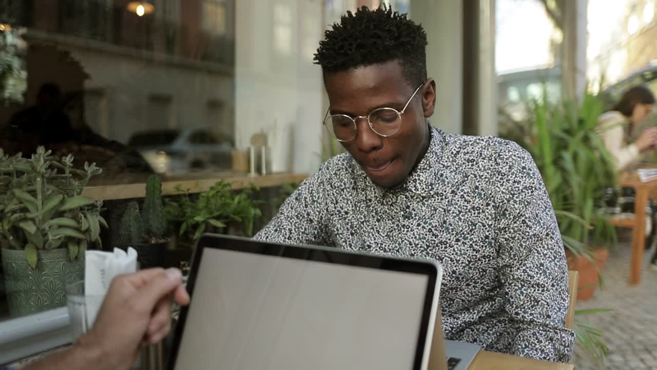 Smiling African American man using laptop in cafe