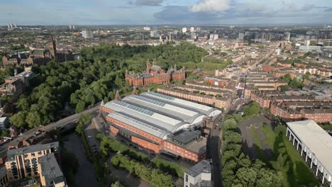 aerial fly towards kelvin hall museum in natural parkland with kelvingrove art gallery and museum in background, glasgow, scotland, uk