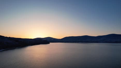 Japanese-Sunrise-Over-Snowy-Hills-And-Cold-Lake-In-Winter-Drone