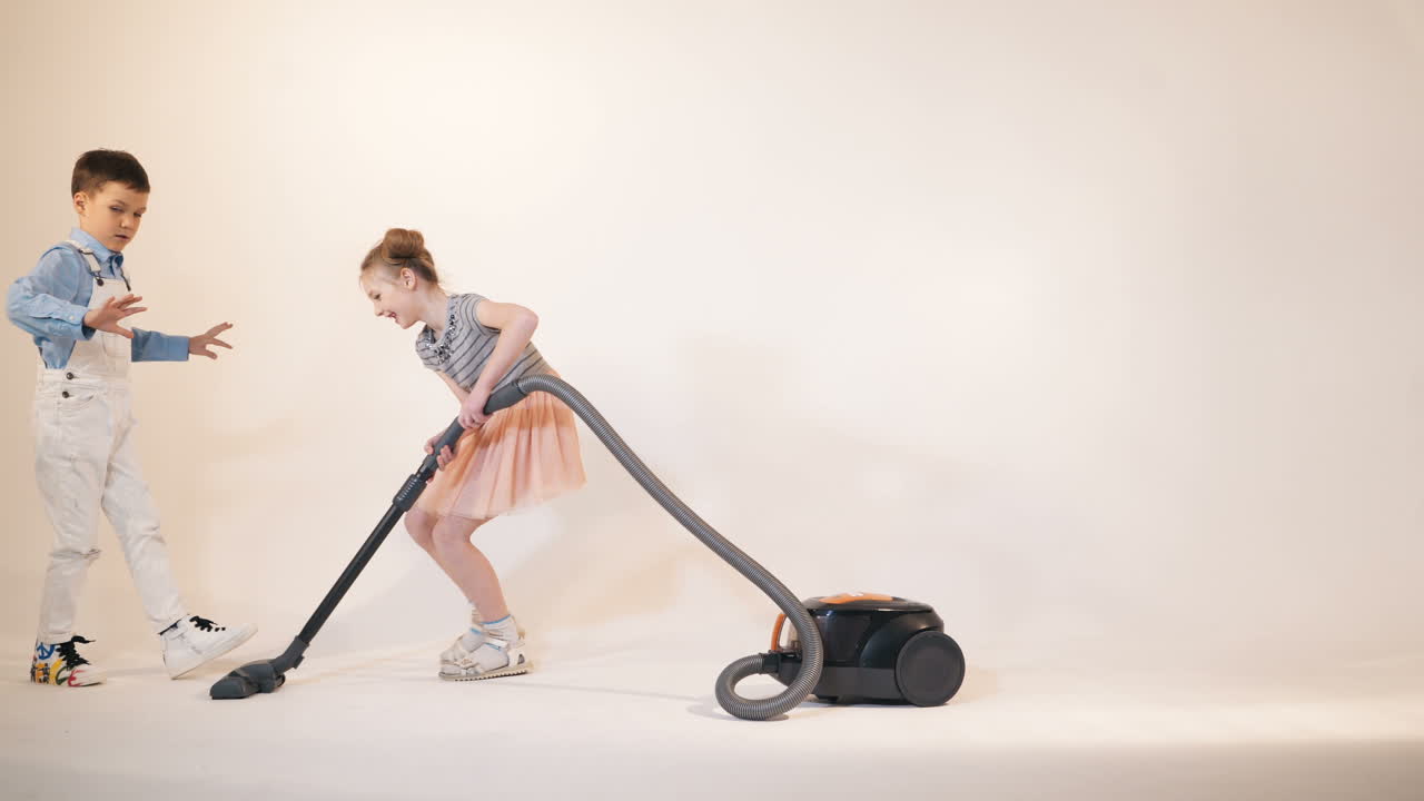 Little children play with a vacuum cleaner. Emotions of the child. Studio shooting of children.