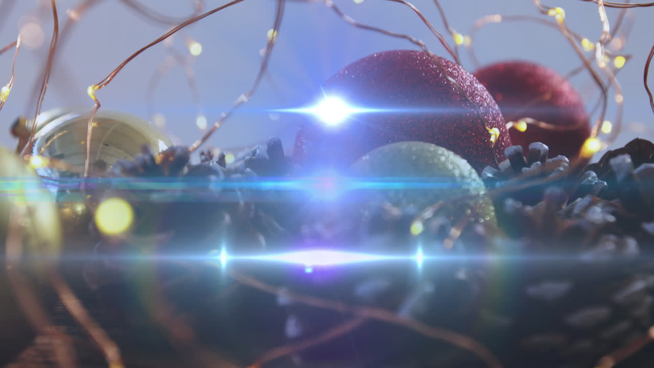 Animation of glowing lights moving over christmas baubles and decorations