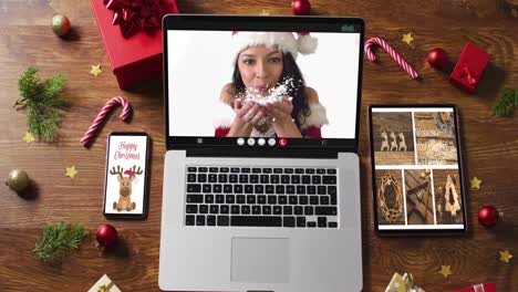 Caucasian-woman-in-santa-costume-on-video-call-on-laptop,-with-smartphone,-tablet-and-decorations