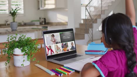 Schoolgirl-using-laptop-for-online-lesson-at-home,-with-diverse-teacher-and-class-on-screen