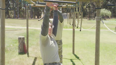Diverse male and female soldier hanging on trapeze bars at army style obstacle course in the sun